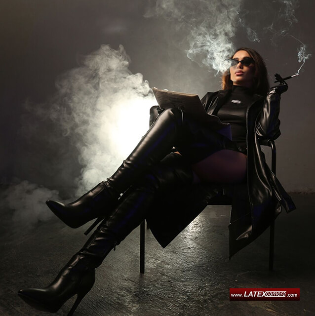 Leather Dominatrix enjoys a smoke while reading