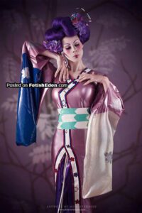 Model in a purple latex kimono outfit standing in a modern indoor room with soft lighting.