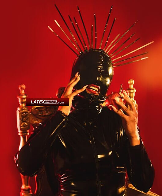 Black PVC Mohawk hooded Mistress in black PVC catsuit with an apple pierced with nails