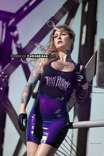 The electric rebellion of transparent purple latex mini-skirt beneath steel beams and untamed blonde hair