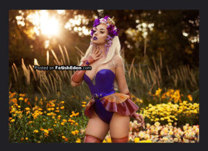 Lotte Lavey posing in a purple latez bodysuit with a translucent mini-skirt, matching translucent gauntlets, and floral headpiece in a sunlit flower garden.