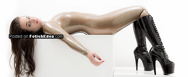 Babe lying on white cube wearing beige latex catsuit and long black PVC boots Fetish model reclining in a glossy nude-beige latex catsuit and tall black lace-up platform boots with extremely high stiletto heels.